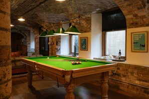 A billiards table in a room with brick walls and a high ceiling.