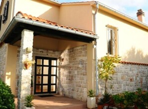 Welcome to a charming standalone building with a covered entrance and a tiled roof.