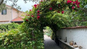 A narrow stone pathway flanked by lush greenery and a flowering archway. - Holiday Home Mirta - Three Bedroom Holiday Home with terrace (Murter)