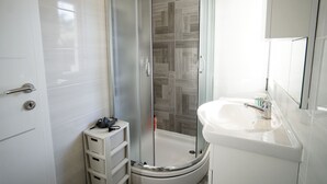 A modern bathroom with a glass-enclosed shower, a white sink, and a storage unit. - Apartments Silver Shade - One Bedroom Apartment with Terrace(a1) (Zadar)