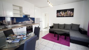 A modern living room with a glass dining table, grey sofa, and a cityscape painting on the wall. - Apartments Silver Shade - One Bedroom Apartment with Terrace(a1) (Zadar)