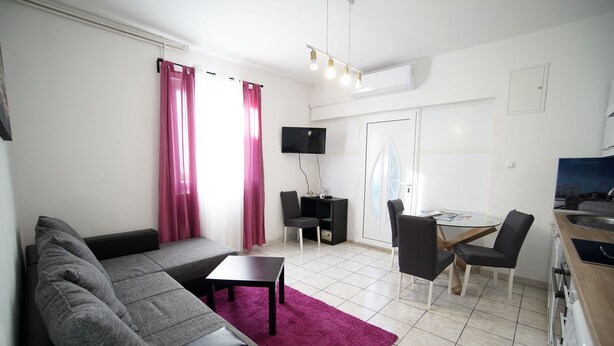A modern living room with a gray sofa, a small table, and a dining area with chairs. - Apartments Silver Shade - One Bedroom Apartment with Terrace(a1) (Zadar)