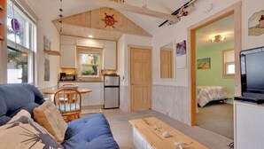 A cozy living room with a sofa, a wooden coffee table, and a television. - Sea Bisquit Cottage by the Ocean (Scarborough)