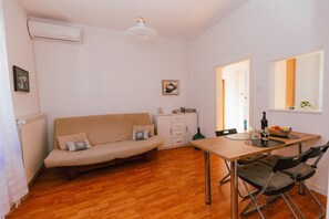 Una sala de estar acogedora con un sofá, una mesa de comedor con sillas, un radiador y un cuadro en la pared.