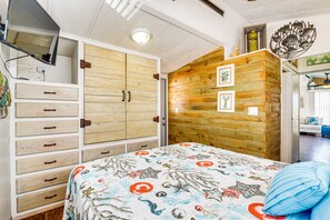 Ein Schlafzimmer mit einem Bett, einem Holzschrank und einer Wand mit gerahmten Bildern.