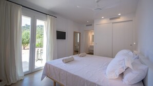 Un dormitorio con una cama grande, una puerta corrediza al balcón y un ventilador de techo.
