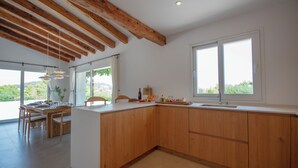 Una cocina moderna con armarios de madera, un ventanal grande y un comedor con luz natural.
