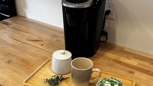 Eine Küchenarbeitsplatte mit Kaffeemaschine, Tasse, Teekanne und einem Tablett mit Teebeuteln.