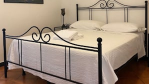 A single bed with a metal frame and white bedding in a room with tiled flooring.