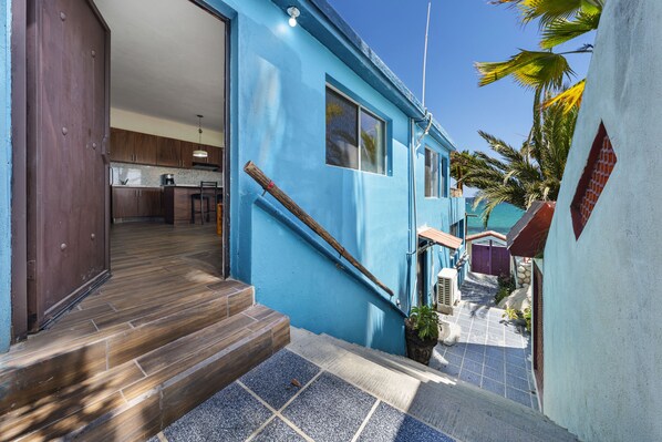 Ein blaues Haus mit einer Holztreppe, die zu einem Küchenbereich führt.