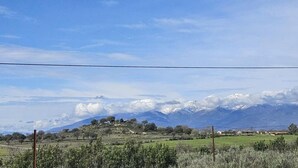 A rural landscape with a mountain range in the background, a clear sky, and a fence in the foreground. - Casa Rural (Candeleda)