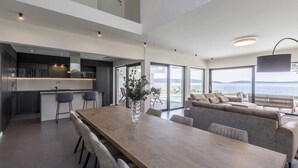 Et moderne køkken med spiseplads og en stor sofa med udsigt over havet.