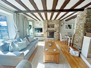 A cozy living room with a stone fireplace, a sofa, a coffee table, and a dining area.