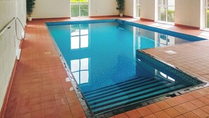 A swimming pool with a tiled deck, a window, and a plant. - Discover a cosy two-bedroom cottage on the Colmer Estate in Ivybridge. (Ivybridge)