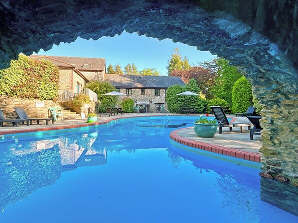 A swimming pool with lounge chairs and a stone building in the background.