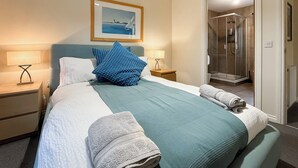 A hotel room with a bed, two bedside tables, a framed picture on the wall, and a shower area. - 4 bedroom accommodation in Balmaha (Balmaha)