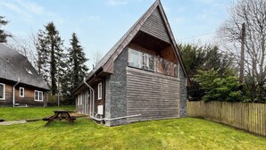 A modern house with a sloped roof, a balcony, and a stone facade. - 4 bedroom accommodation in Balmaha (Balmaha)