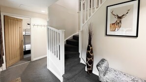 A staircase with white railings leading to a landing. A framed deer picture hangs on the wall. - 4 bedroom accommodation in Balmaha (Balmaha)