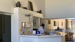 A hotel reception area with a counter, a large vase, and a person behind the counter.