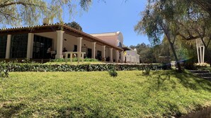 A building with a covered patio, large windows, and a well-maintained lawn.