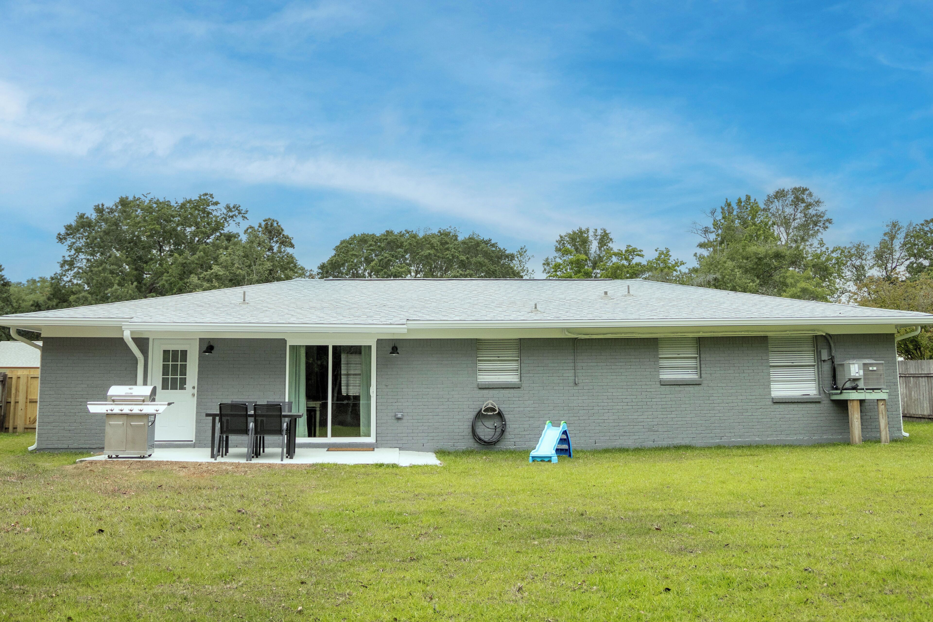 A single-story house with a covered patio, a grill, and a small play area.