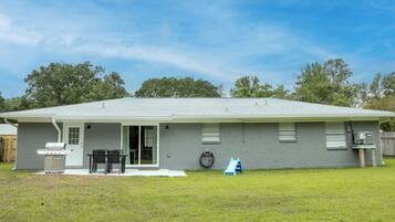 A single-story house with a covered patio, a grill, and a small play area.