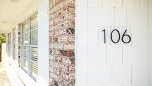 L’extérieur d’un bâtiment, avec un mur en briques et un mur blanc sur lequel est inscrit le numéro 106.