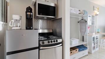 A compact kitchen with a refrigerator, stove, microwave, and coffee maker.