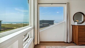 Un dormitorio con un amplio ventanal que ofrece vistas a la playa y edificios.