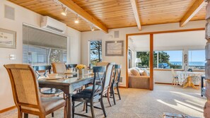 A dining area with a wooden ceiling, a large window with blinds, and a view of the sea. - Sea Cliff by Manzanita Beach Getaway: Hot Tub, Stunning Views, Allergen-Free (Manzanita)