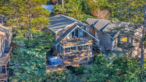 A two-story house with a balcony and a deck, surrounded by dense trees. - Sea Cliff by Manzanita Beach Getaway: Hot Tub, Stunning Views, Allergen-Free (Manzanita)