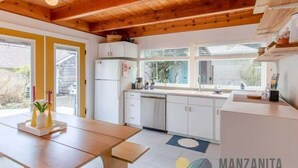 Una cocina moderna con vigas de madera, armarios blancos y un amplio ventanal.