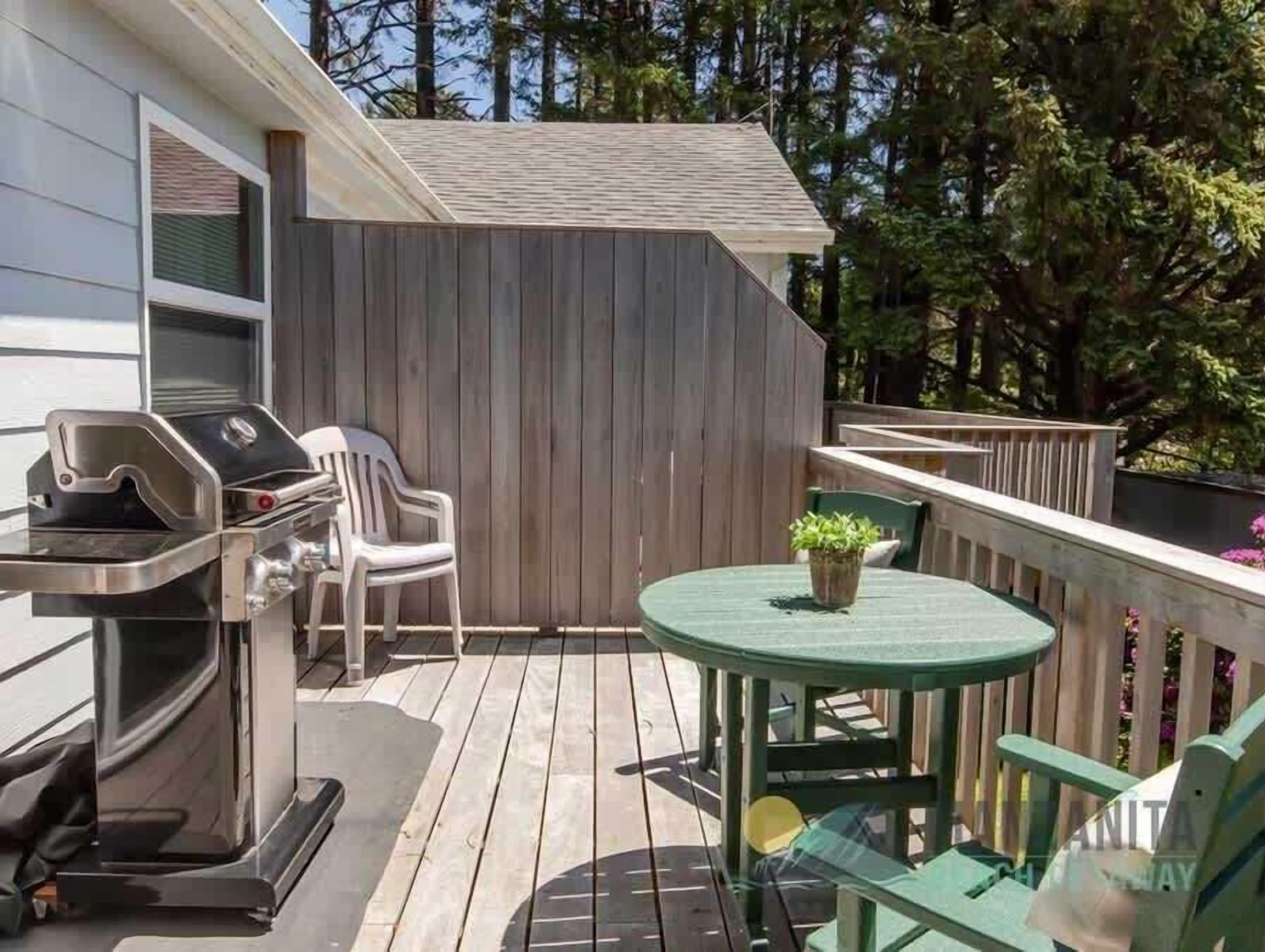 A deck with a grill, chairs, and a table.