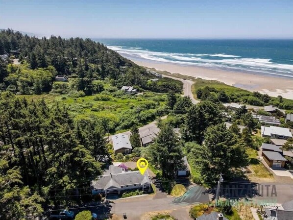 An aerial view of a coastal residential area with houses, a beach, and dense forest. - SeaView by Manzanita Beach Getaway: Ocean View, Private Apt, Allergen-Free (Nehalem)