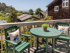 A balcony with a green table and chairs, a potted plant, and a view of houses and trees. - SeaView by Manzanita Beach Getaway: Ocean View, Private Apt, Allergen-Free (Nehalem)