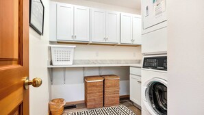 Een wasserette met een wasmachine, een droger en een plank met een mand.