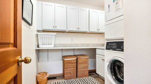 Een wasserette met een wasmachine, een droger en een plank met een mand.