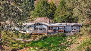 Une maison moderne dotée d’une terrasse, de grandes fenêtres et d’une cheminée en pierre.