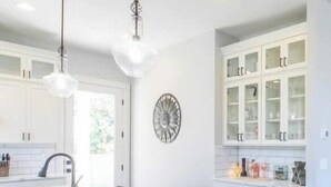 A modern kitchen with a large island, white cabinetry, and a built-in dishwasher. - Light House by Manzanita Beach Getaway: High-End w/ Ocean & Neahkahnie Views (Manzanita)