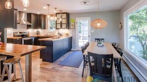 Une cuisine moderne avec des plans de travail en bois, un îlot central et des luminaires suspendus.