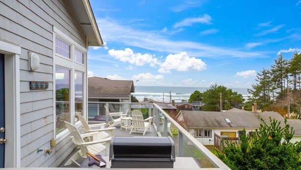 A balcony with white chairs, a grill, and a view of the ocean. - Coastal View by Manzanita Beach Getaway: Ocean Views, Dog-Friendly & Great Deck (Neahkahnie)