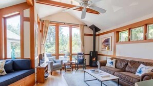 Un salon chaleureux avec une cheminée, des meubles en bois et de grandes fenêtres.