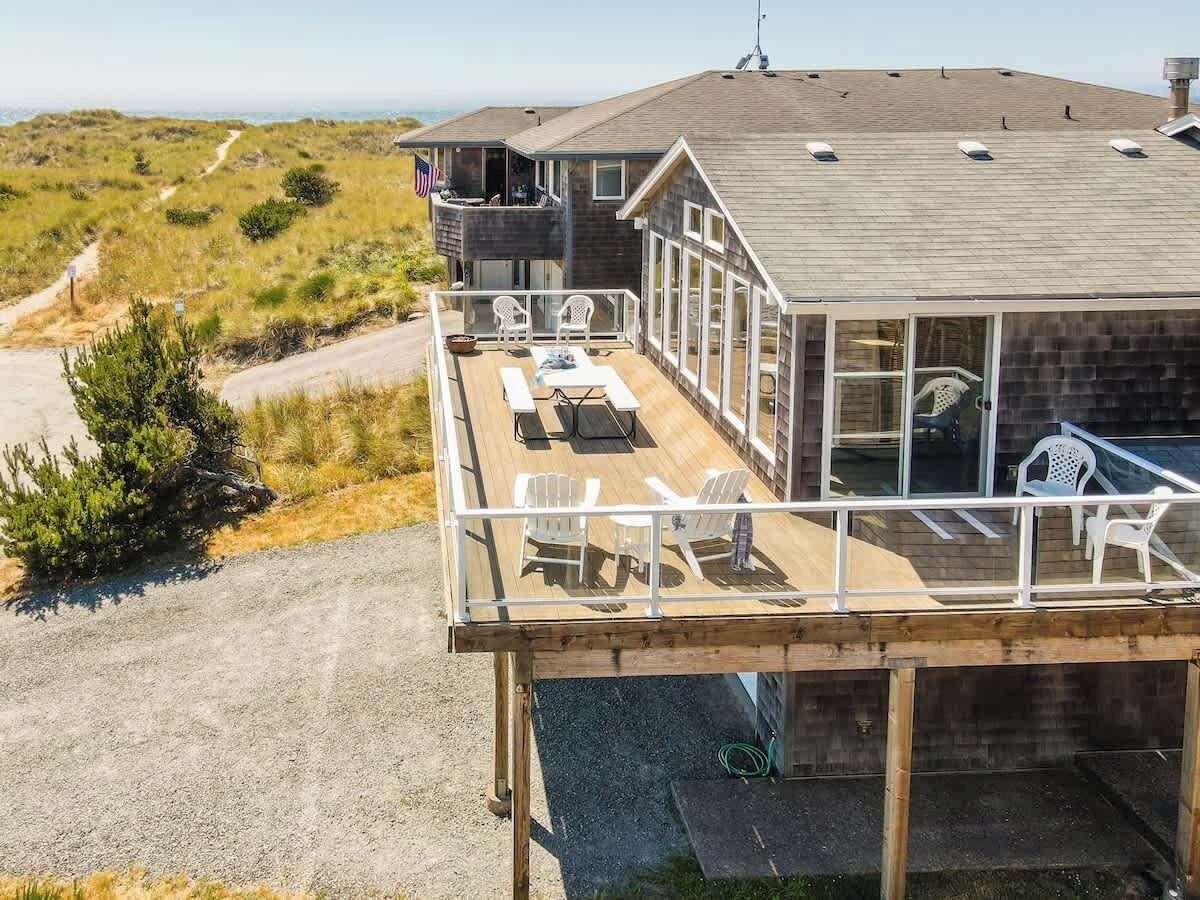 Una casa de dos pisos con un balcón, mobiliario exterior y vistas del paisaje.