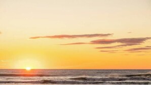 Ein Sonnenuntergang über dem Meer mit Wellen.