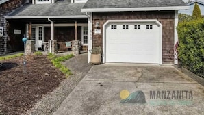 Ein zweistöckiges Haus mit Garage, überdachter Veranda und begrüntem Auffahrt.