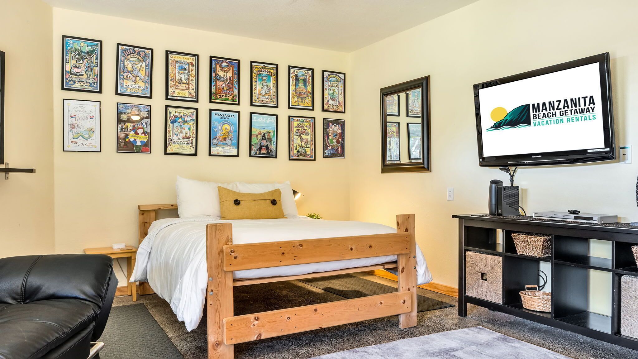 Ein Schlafzimmer mit einem hölzernen Bett, einem schwarzen Ledersessel, einem Fernseher und gerahmten Postern an der Wand.