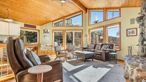 A spacious living area with leather chairs, a sofa, and a dining table. Large windows provide views of the outdoors. - Legasea on the Pond by Manzanita Beach Getaway: Dog-Friendly, Scenic Views (Nehalem)
