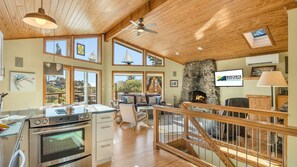 Un'ampia cucina con piano cottura moderno, zona pranzo con tavolo e sedie in legno, camino in pietra e ampie finestre con vista sull'esterno.