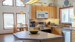 Une cuisine moderne avec des meubles en bois, un four à micro-ondes, une cuisinière et un grand îlot central doté d’un évier.