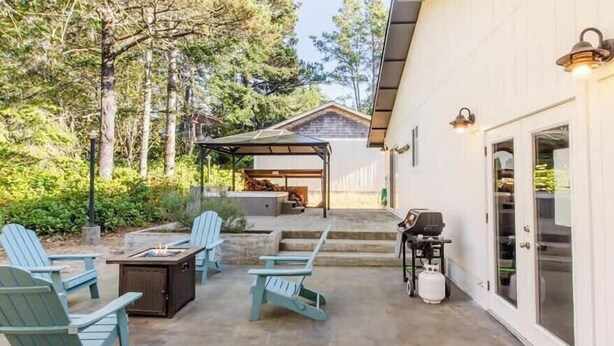Un patio al aire libre con sillas Adirondack, una parrilla y un área de estar cubierta.
